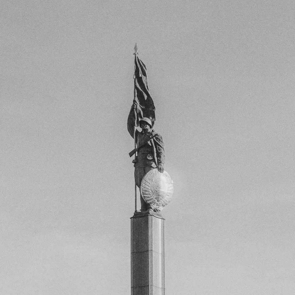 Black-and-white view of a soldier statue atop a tall stone column in Vienna