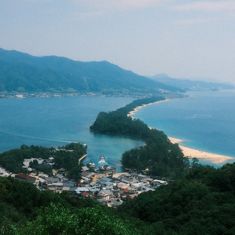 The wooded Amanohashidate sandbar stretching across blue water, seen from a hillside