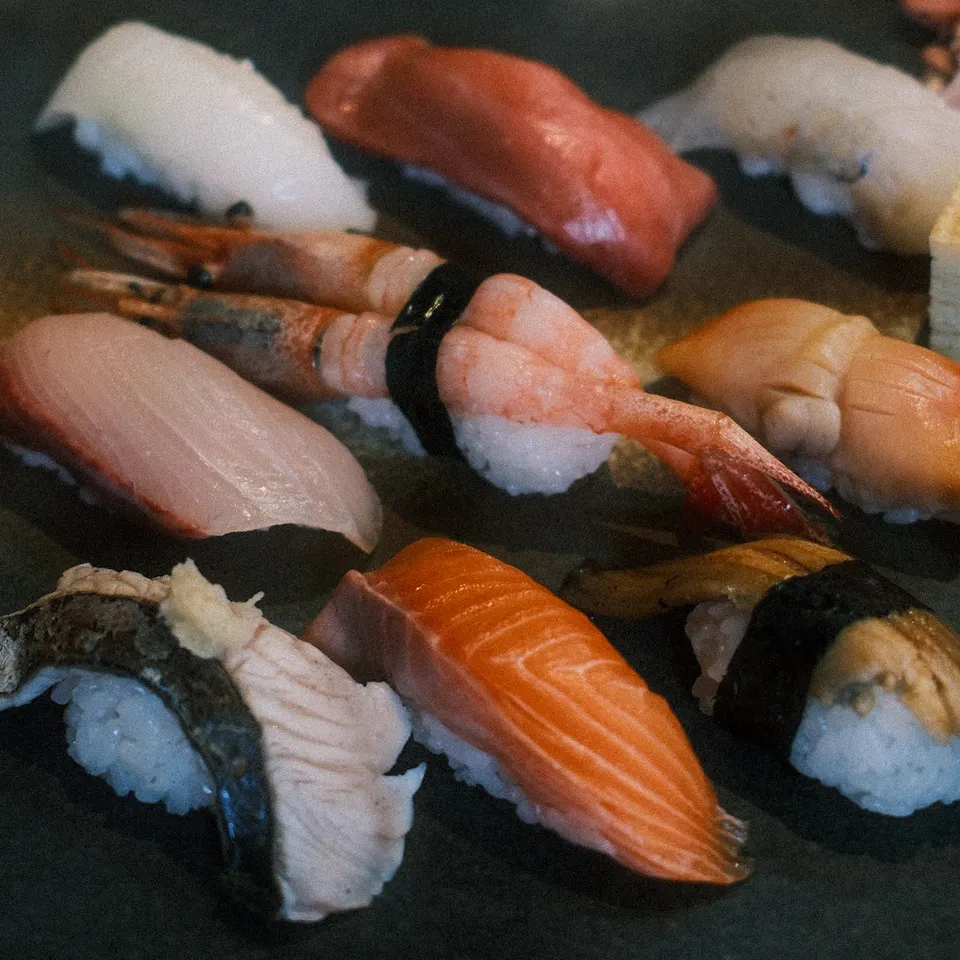 Assorted nigiri sushi arranged on a dark rectangular plate
