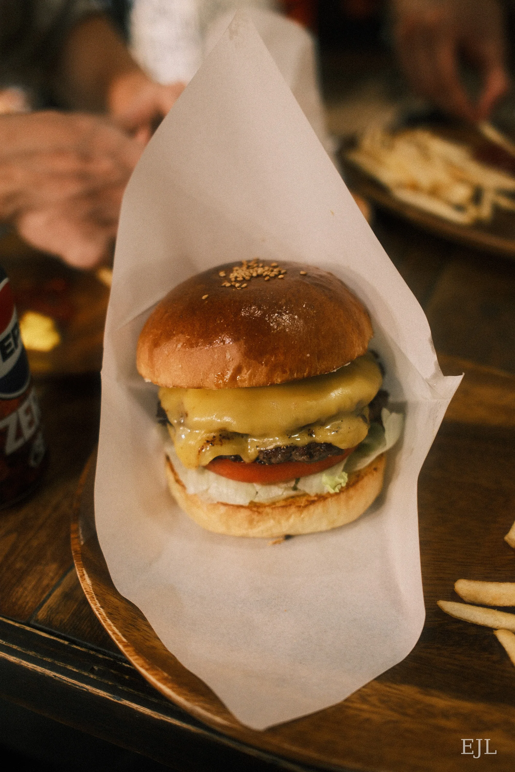 A cheeseburger with a glossy bun, lettuce and tomato in a paper-lined basket