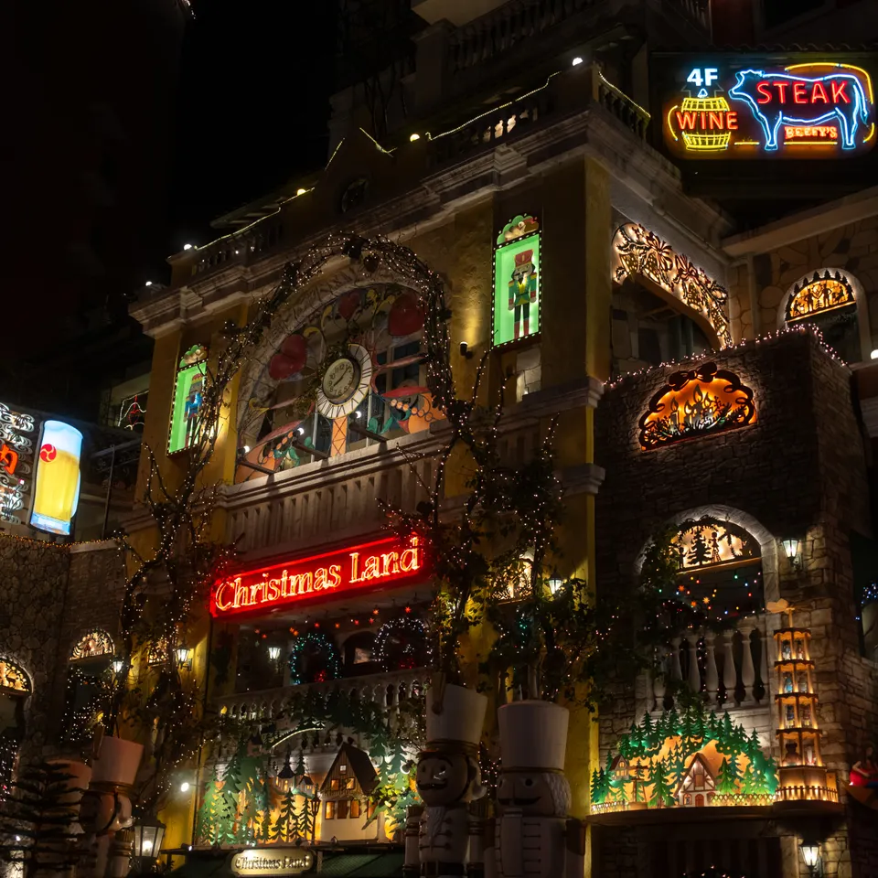 The Christmas Land storefront glowing with decorative lights and colourful signs at night