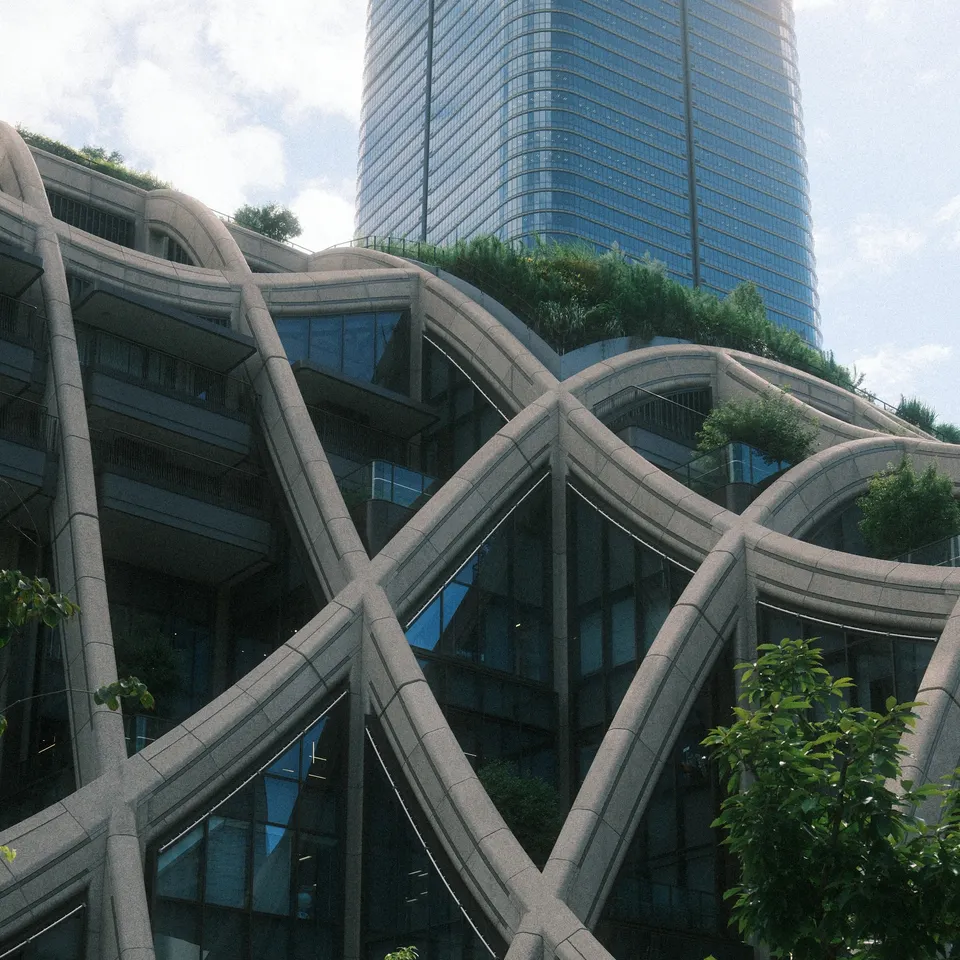 Curving concrete latticework and planted terraces at Azabudai Hills, with a tower behind